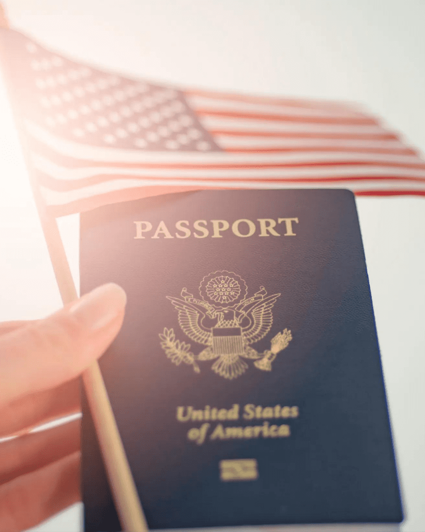 A person holding their passport in front of an american flag.