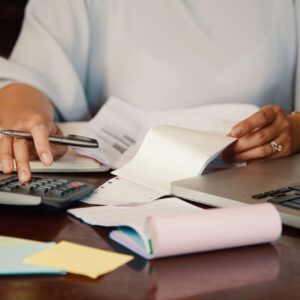 A person sitting at a table with papers and calculators.