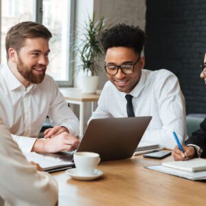 A group of people sitting around a table with laptops.