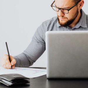 A man writing on paper while sitting at a table.