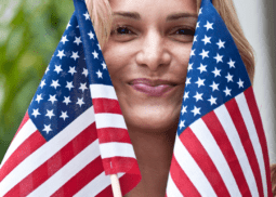 A woman holding two american flags in front of her face.